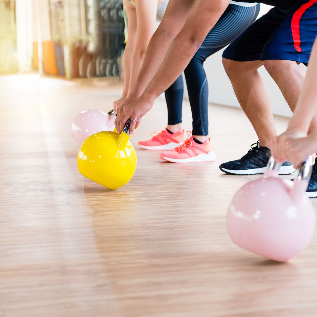 2 people using kettlebells one yellow and one pink